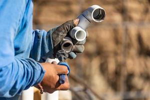 Plumber Applying Pipe Cleaner, Primer and Glue to PVC Pipe At Construction Site photo