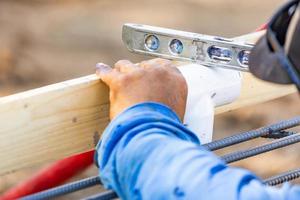 fontanero usando nivel mientras instala tubería de pvc en el sitio de construcción foto