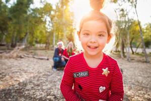 Linda niña de raza mixta retrato de Navidad con la familia detrás al aire libre foto