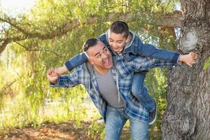 Mixed Race Father And Son Having Fun Piggy Back Outdoors photo