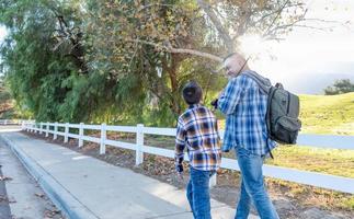 Mixed Race Father And Son Outdoors Walking With Fishing Poles photo