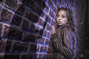 Male Shadow Figure With Knife Threatens Frightened Young Woman Against Brick Wall photo