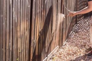 Professional Painter Spraying Yard Fence with Stain photo