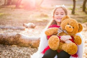 Cute Young Mixed Race Girl Hugging Teddy Bear Outdoors photo