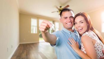 Young Military Couple with House Keys In Empty Room of New Home photo