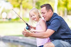 joven caucásico padre e hija divirtiéndose pescando en el lago foto