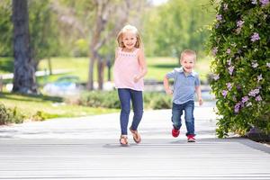 hermana joven y hermano divirtiéndose corriendo en el parque foto