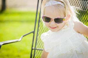 Cute Playful Baby Girl Wearing Sunglasses Outside at Park photo