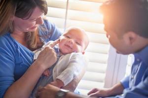 Happy Mixed Race Couple Enjoying Their Newborn Son In The Light of The Window. photo