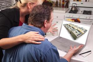 Couple In Kitchen Using Laptop - Money photo