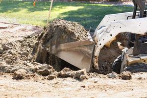 Small Bulldozer Digging In Yard For Pool Installation photo