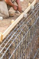 Worker Securing Steel Rebar Framing With Wire Plier Cutter Tool At Construction Site photo