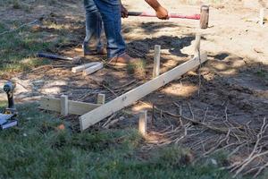 Worker Installing Stakes and Lumber Guides At Construction Site photo