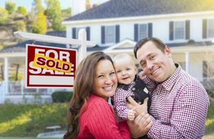 Young Family In Front of For Sale Sign and House photo