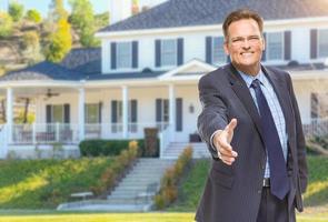 agente masculino alcanzando un apretón de manos frente a la casa foto