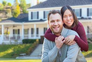 Mixed Race Caucasian and Chinese Couple In Front Yard of Beautiful Custom House. photo