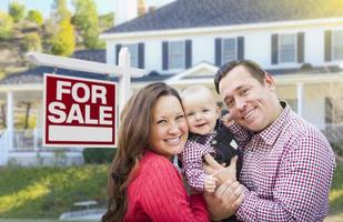 Young Family In Front of For Sale Sign and House photo