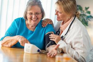 Senior Adult Woman Learning From Female Doctor to Use Blood Pressure Machine photo