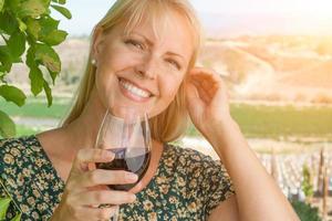 hermosa joven adulta disfrutando de una copa de cata de vinos en el viñedo foto