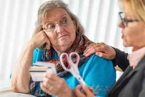 consultor financiero entregando tijeras a una anciana con tarjetas de crédito foto