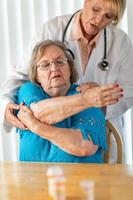 Female Doctor Helping Senior Adult Woman With Arm Exercises photo