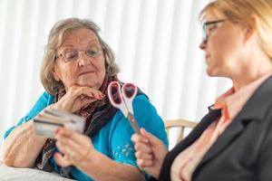 Financial Consultant Handing Scissors to Senior Lady Holding Credit Cards photo