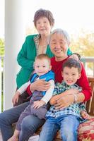 pareja china adulta mayor sentada con sus nietos de raza mixta foto