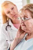 mujer adulta mayor melancólica siendo consolada por una doctora o enfermera foto