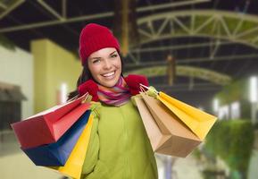 cálidamente vestida mujer de raza mixta con bolsas de compras foto