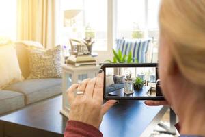 mujer tomando fotos de una sala de estar en una casa modelo con su teléfono inteligente