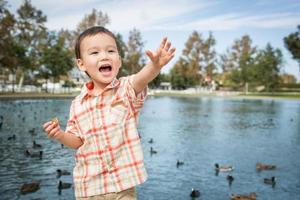 joven chino y caucásico divirtiéndose en el parque y estanque de patos. foto