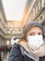 mujer joven con mascarilla camina cerca de la galería uffizi en italia foto