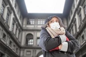 mujer joven con mascarilla camina cerca de la galería uffizi en italia foto