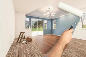 Before and After of Man Painting Roller to Reveal Newly Remodeled Room with Fresh Blue Paint and New Floors. photo