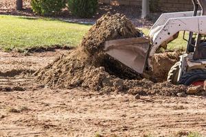 Small Bulldozer Digging In Yard For Pool Installation photo