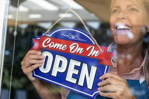 Happy Female Store Owner Turning Open Sign in Window photo