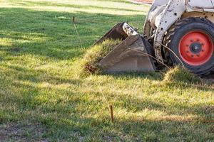 Small Bulldozer Removing Grass From Yard Preparing For Pool Installation photo