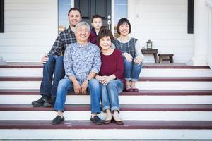 familia china y caucásica sentada en el porche delantero foto