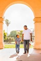 feliz padre afroamericano e hijo de raza mixta caminando en el parque foto