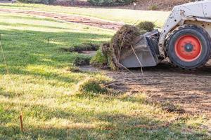 excavadora pequeña quitando hierba del patio preparándose para la instalación de la piscina foto