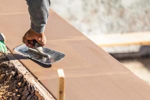 Construction Worker Using Trowel On Wet Cement Forming Coping Around New Pool photo