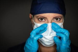 Female Doctor or Nurse Wearing Surgical Gloves Putting On Medical Face Mask photo