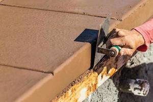 Construction Worker Using Stainless Steel Edger On Wet Cement Forming Coping Around New Pool photo