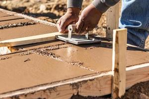 trabajador de la construcción usando una ranuradora manual en cemento húmedo formando una nueva piscina foto