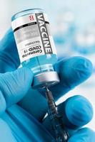 Doctor or Nurse Wearing Surgical Glove Holding Coronavirus COVID-19 Vaccine Vial and Syringe photo