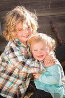 Sweet Little Boy Plays with His Baby Sister in a Rustic Ranch Setting at the Pumpkin Patch. photo