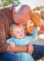 adorable joven familia disfruta de un día en el huerto de calabazas. foto