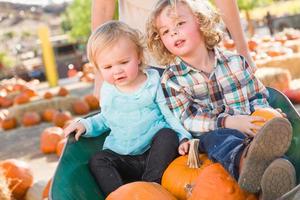 un dulce niño juega con su hermanita en un rancho rústico en el huerto de calabazas. foto