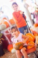 Two Young Girls Riding Wagon with Pumpkins. photo