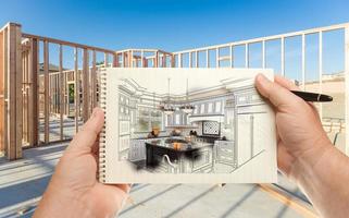 Male Hands Holding Pen and Pad of Paper with Custom Kitchen Illustration Inside Construction Framing. photo